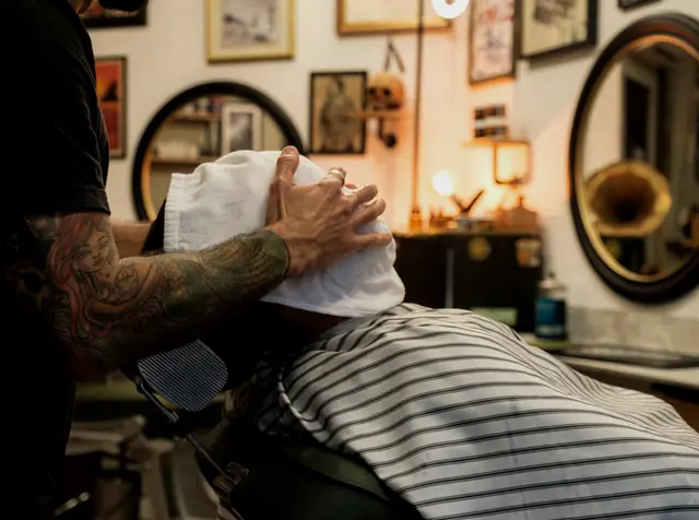 Barber placing a hot towel on a client before a shave