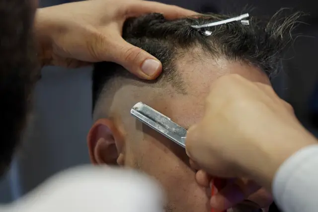 Close-up of a sharp hairline being cut with a straight razor